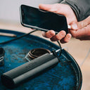 Magicshine MJ-906S Front Bike Light on blue surface with hand holding smartphone nearby
