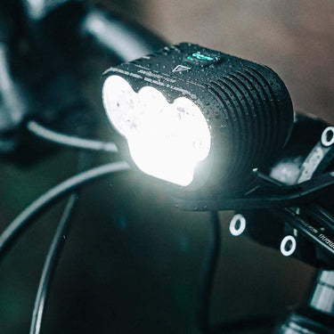 Magicshine Monteer 5000 MTB headlight mounted on bike handlebar with bright light and water droplets